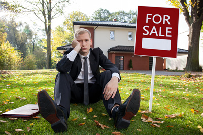 Man pouting in front of two story house